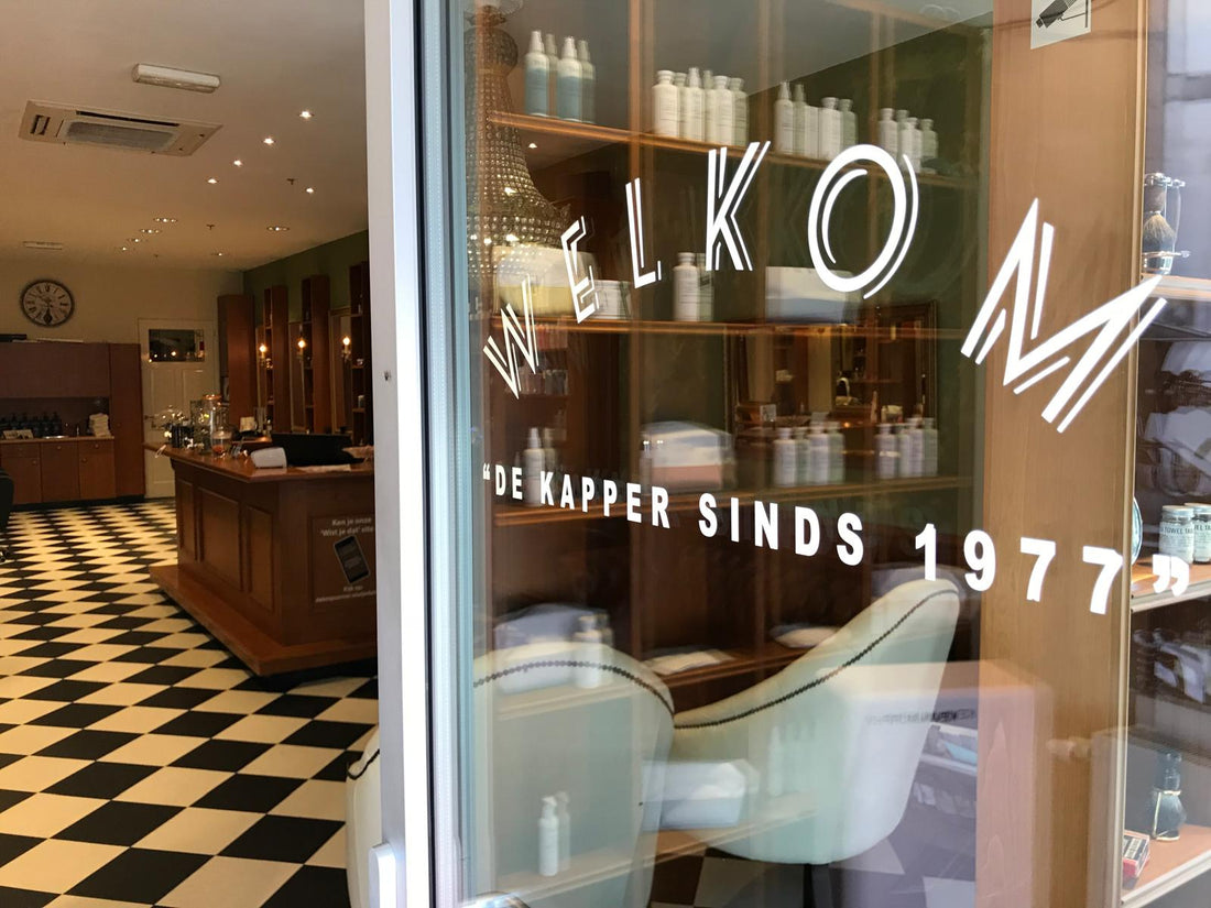 De etalage van De Knipcorner aan De Promesse in Lelystad, met de tekst De kapper sinds 1977 op de ruit